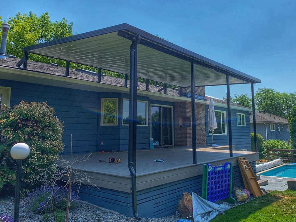large patio cover on blue house beside pool